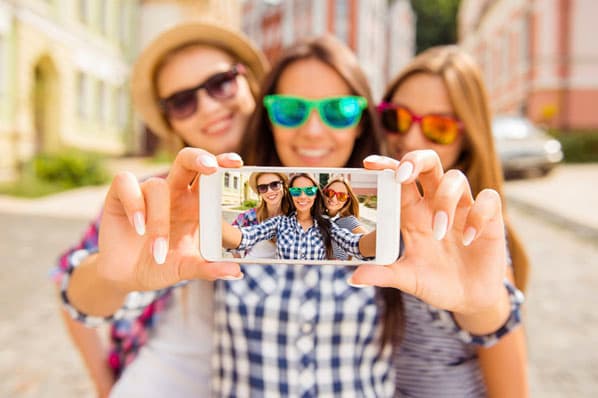 社交媒体营销人员戴着太阳镜微笑着为2021年在最新的社交媒体平台上发布的自拍照